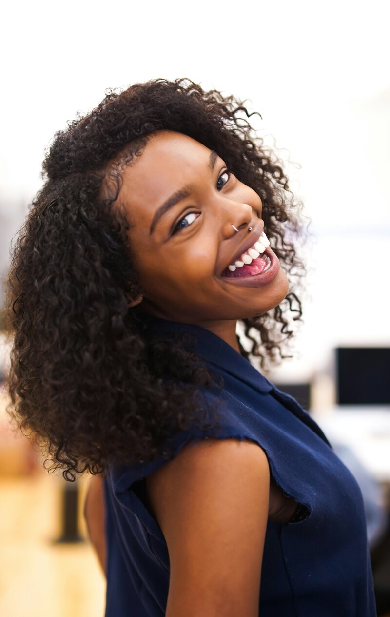 young woman smiling with face piercings and curly hair