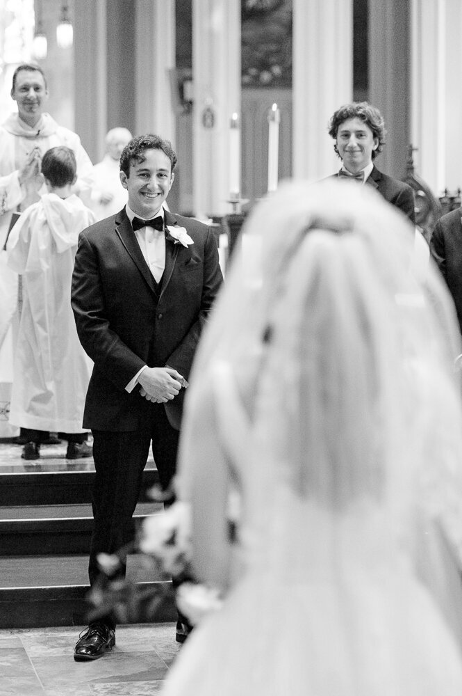 a groom smiling as bride approaches during wedding ceremony