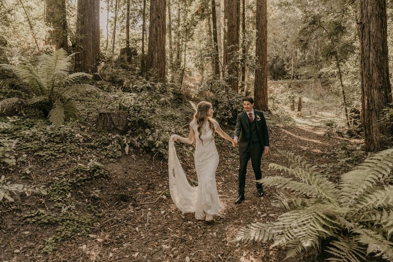 bride and groom walk through forest