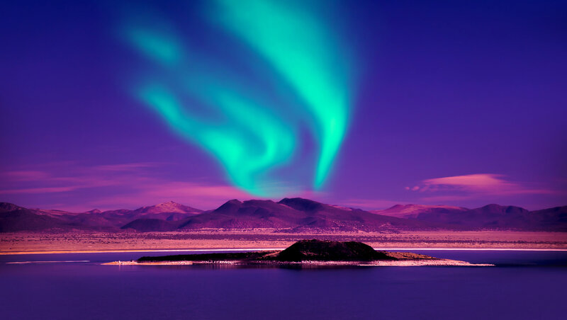 The mesmerizing Northern Lights dance across the Icelandic sky, illuminating a remote wilderness landscape. Experience bespoke glamping under the aurora borealis with high-touch concierge service, curated by Nadia Forte Travel & Events.