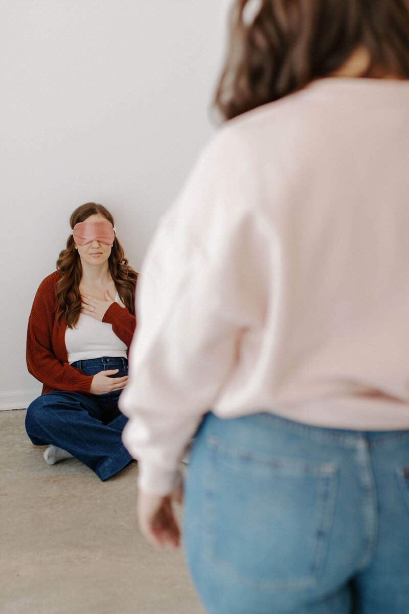 woman sitting with eye mask subconscious reprogramming modalities in red sweater and jeans