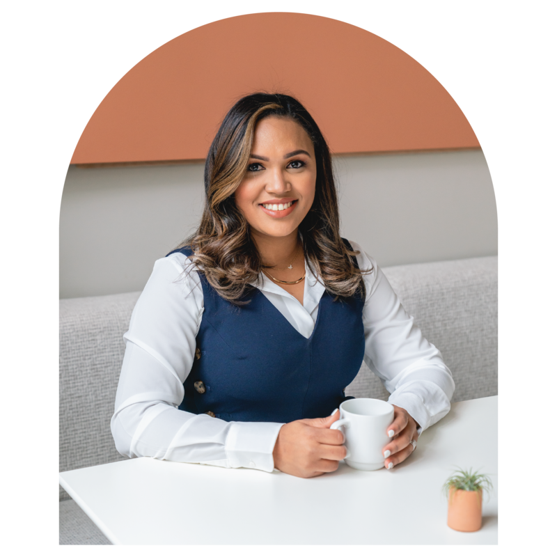 Rossalvi sitting at her desk with a cup of coffee