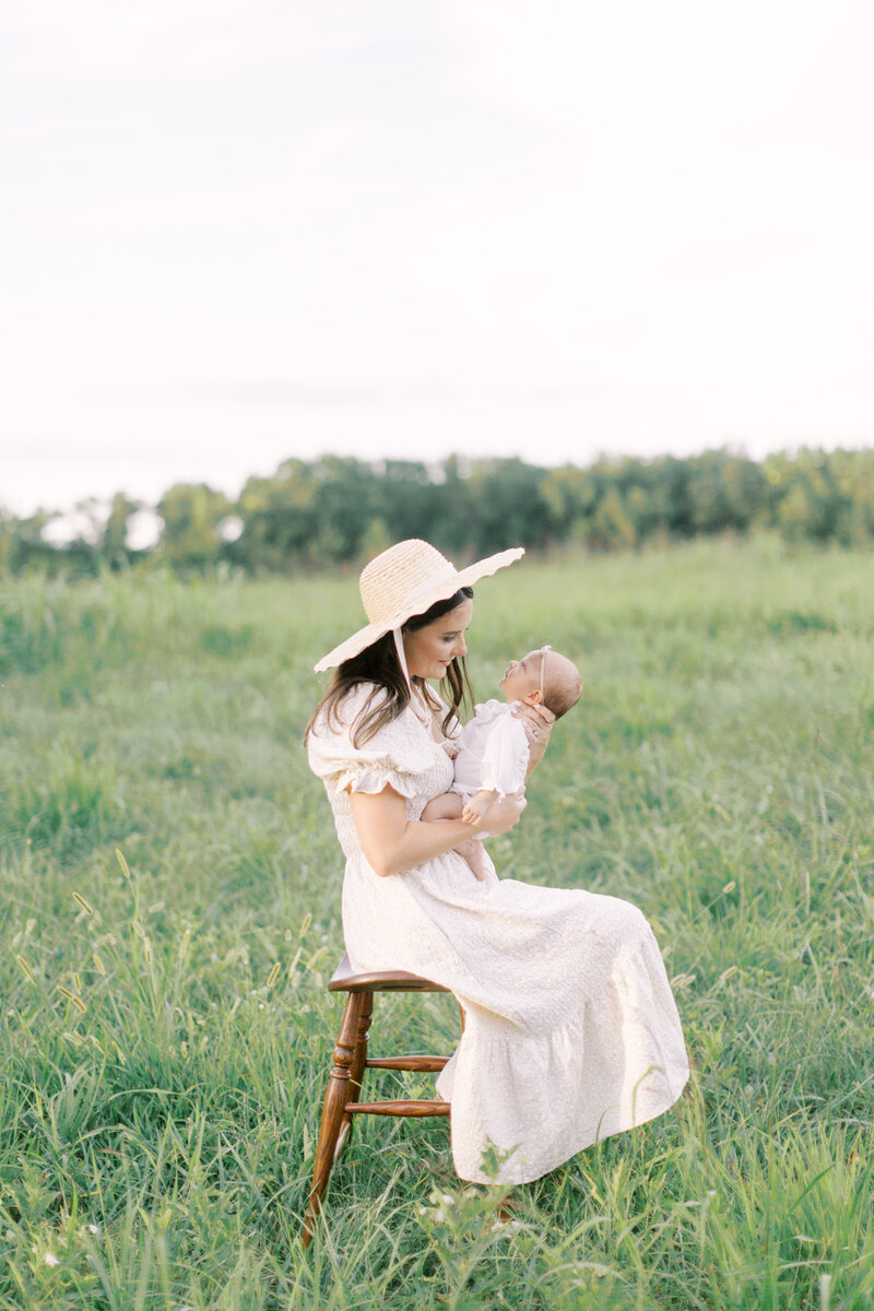 Mother looking at her newborn daughter while sitting in a field of green