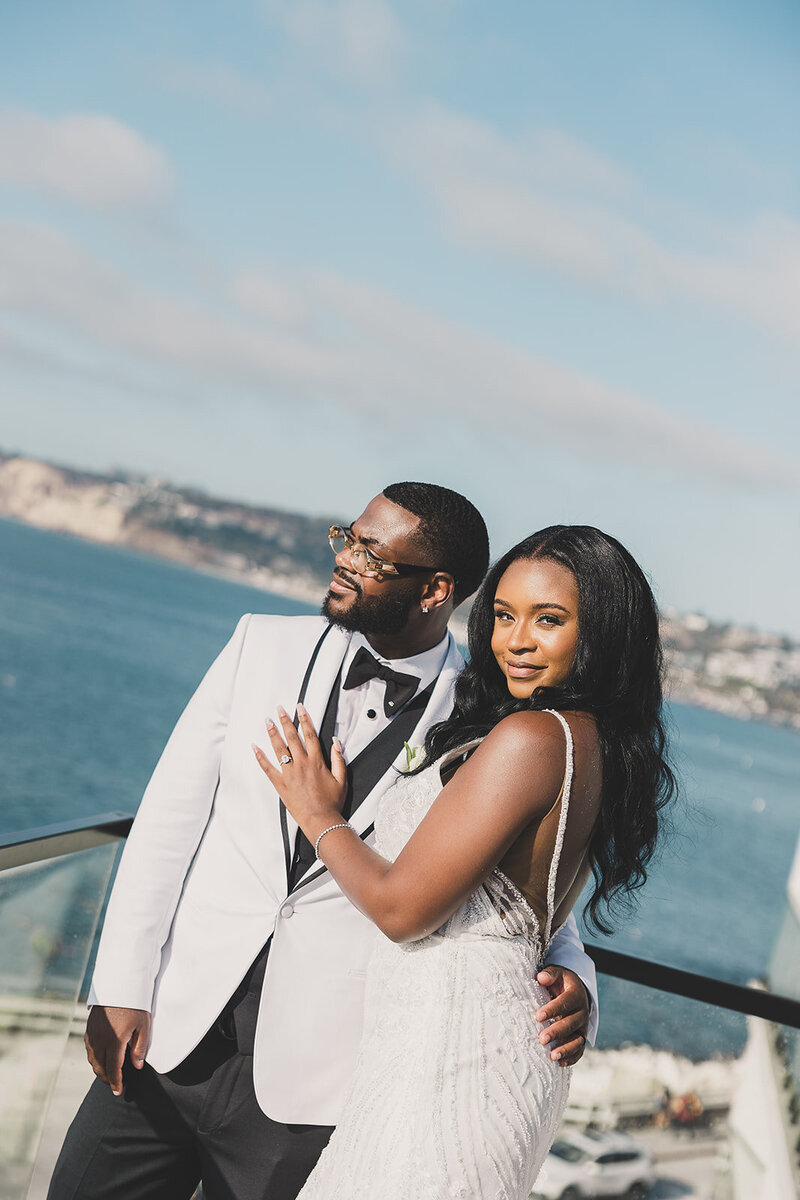 bride and groom embrace next to ocean after destination wedding ceremony