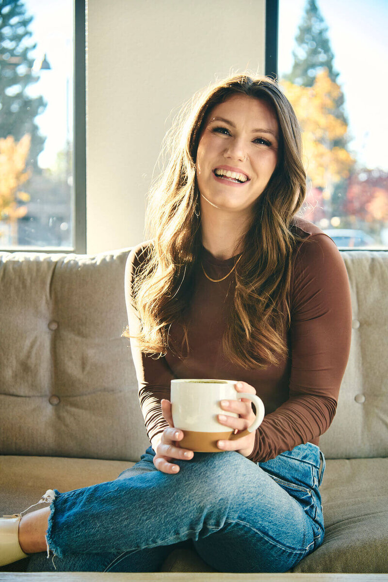 brunette stilling on a couch holding a mug