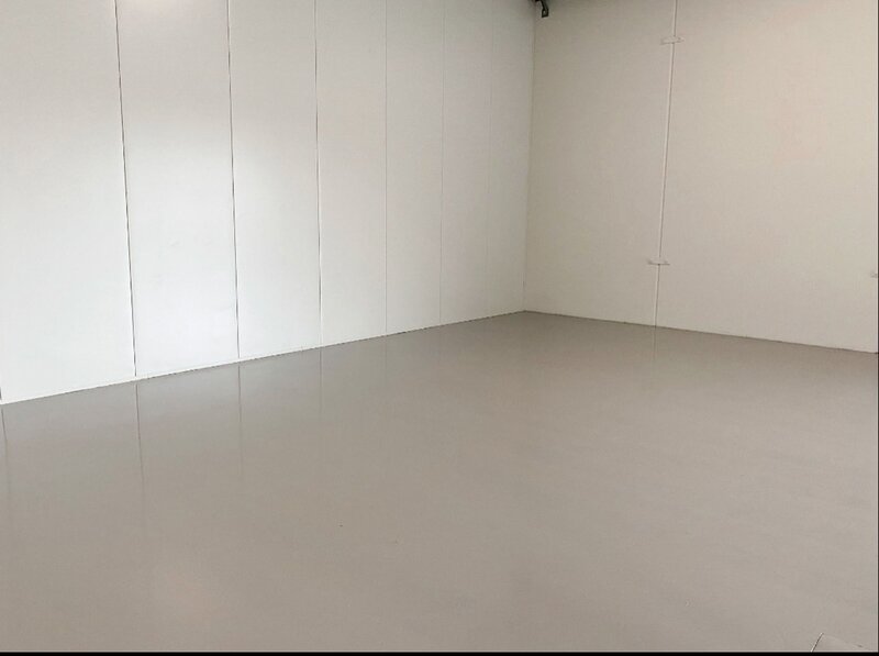 An empty room with white walls and epoxy floors.