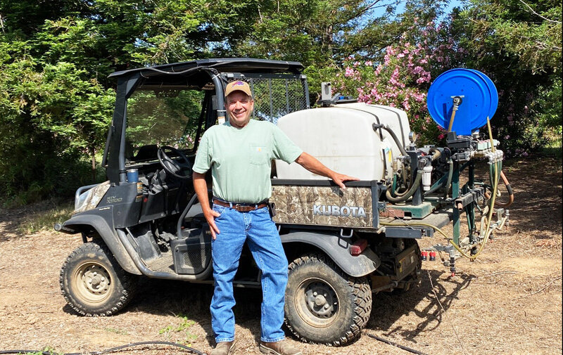 Scott Morrison smiling next to his ATV and vegetation management equipment