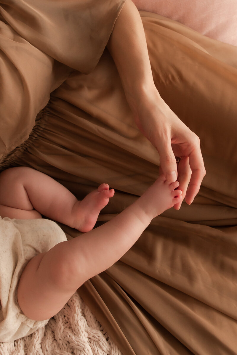A mother holding her little baby's toes.
