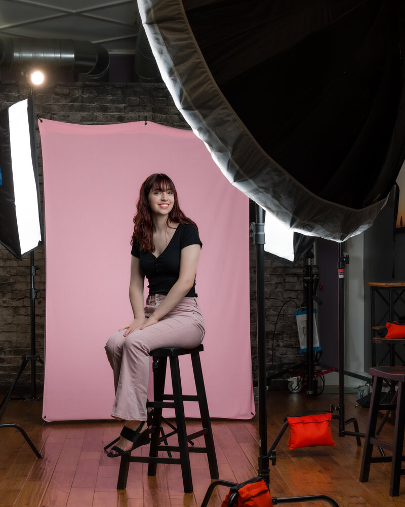 Actor branding shot of a girl sitting on a stool against a brick backdrop in studio