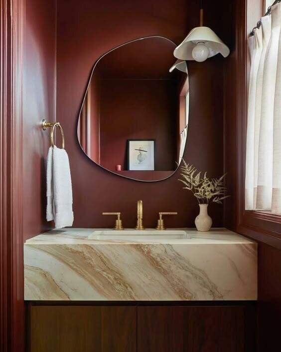 A luxurious bathroom featuring a marble sink and mirror, exuding elegance and sophistication with a touch of confidence in red.