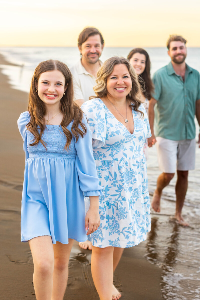 A family of five plays barefoot in a tidal pool at sunset during a Brooke Tucker photography beach session, their reflections visible in water as they explore and connect at the shoreline in Virginia Beach