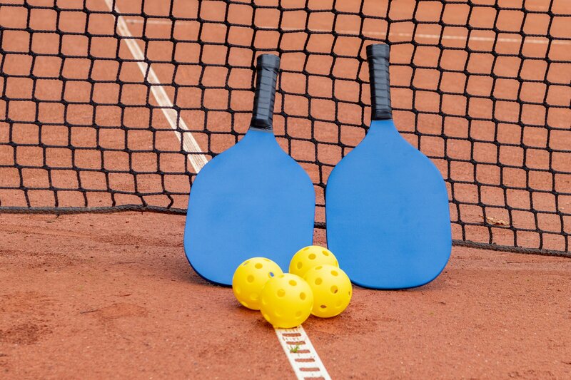 pickleball rackets resting against a net. image credit aleksander-saks unsplash free for use