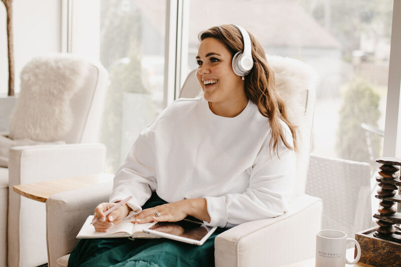 Woman with dark hair whering white shirt and green skirt with white headphones
