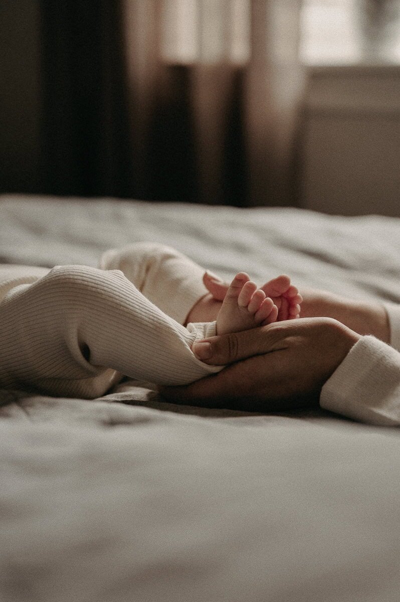 Två bebisfötter ligger i sin mammas händer.