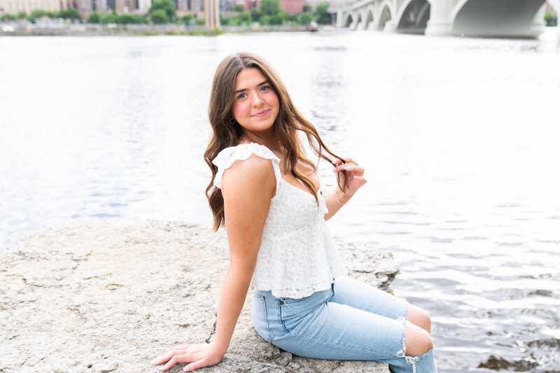 High school girl sits in a flower garden for her senior pictures