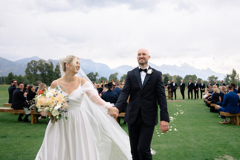 Couple walks beside pond with reflection at their Diamond Cross Ranch Wedding with photography by Foxtails Photography