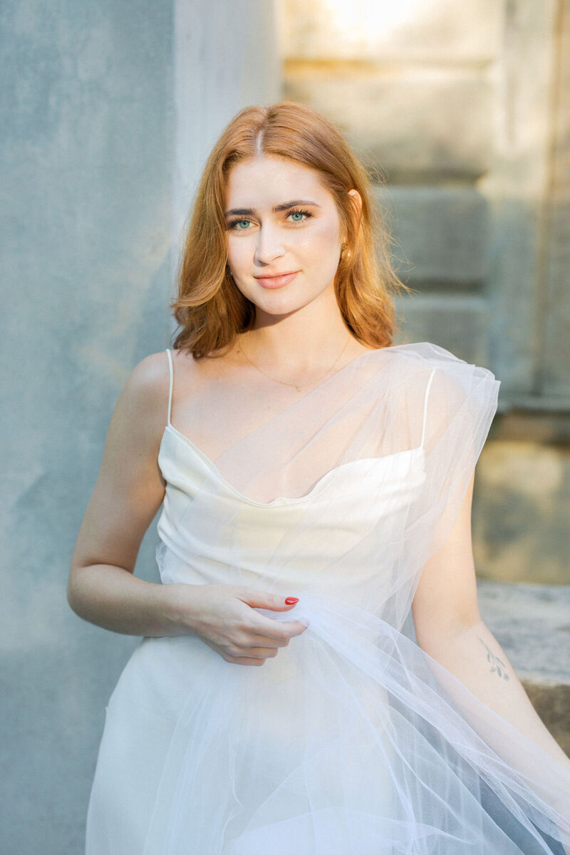 Woman in white dress with red nails and red hair stands outside of Atlanta History Center