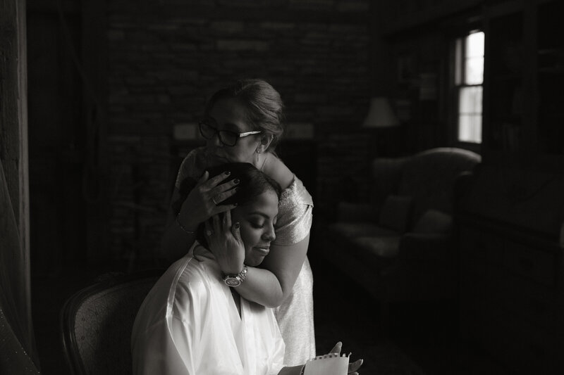 Black and white image of a bride embracing a loved one in a quiet, emotional moment before her wedding, photographed by Rainstorm Photo & Video in Indiana.