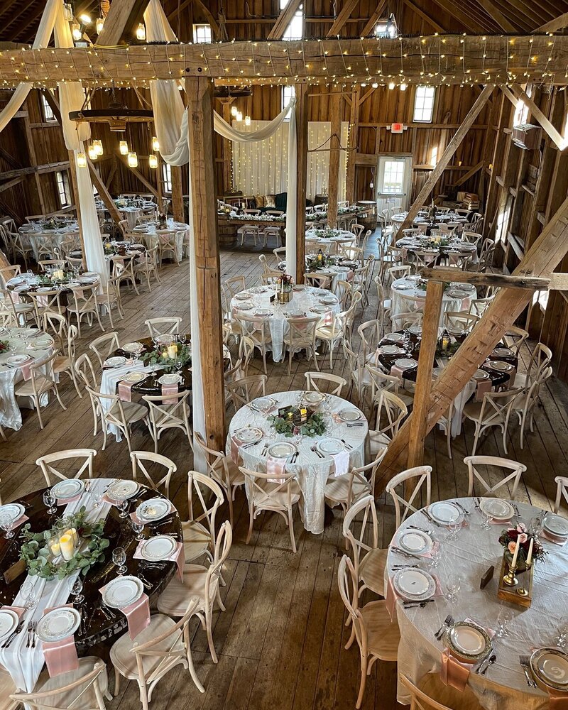 Tables arranged for a wedding reception inside a barn.