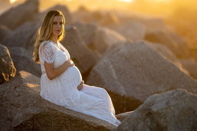 pregnant-mother-in-white-dress-at-sunset-showing-her-baby-bump