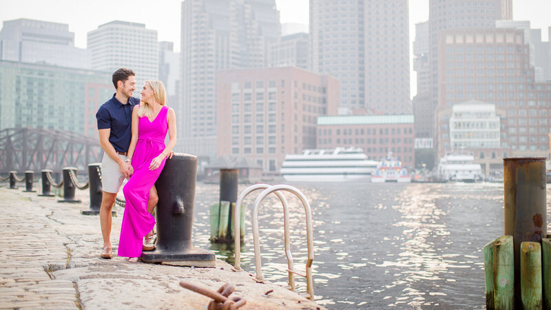 Couple posing with the Boston cityscape behind them, capturing the charm and energy of their destination engagement photography session.