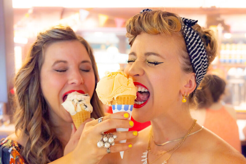 Two woman dressed in classic pinup style fashion eating ice cream cones.