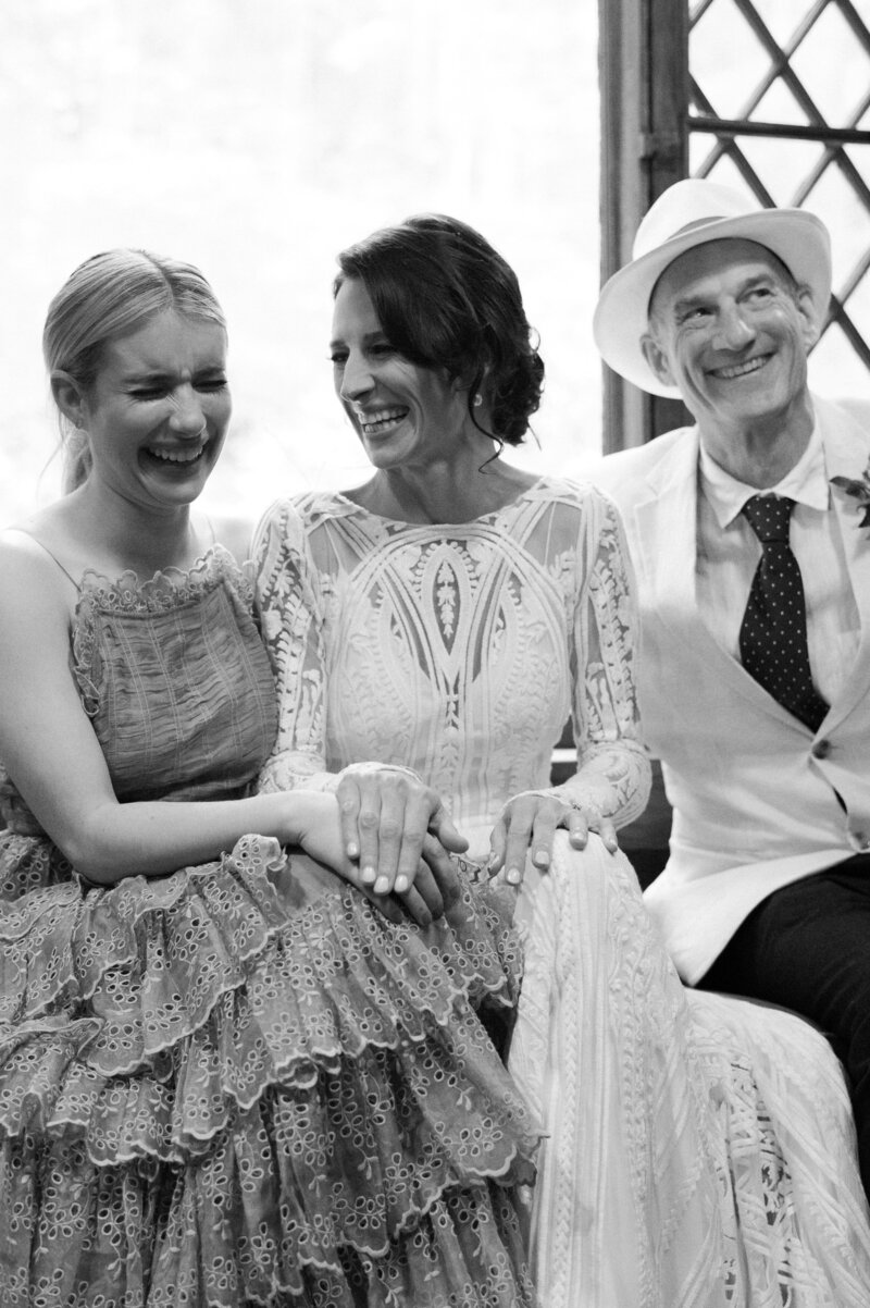 Bride sits with wedding party and they all laugh