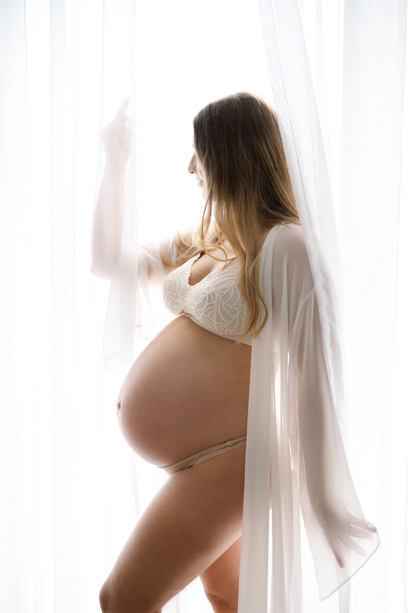Black and white image of pregnant mother looking down at her belly sweetly as photographed by Sydney maternity photographe