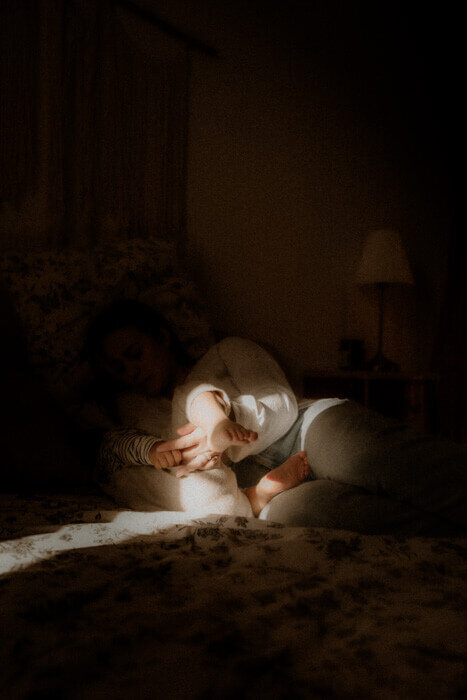 maman et bebe se tiennent la main sur le lit lors de leur seance photo famille a leur domicile a nice