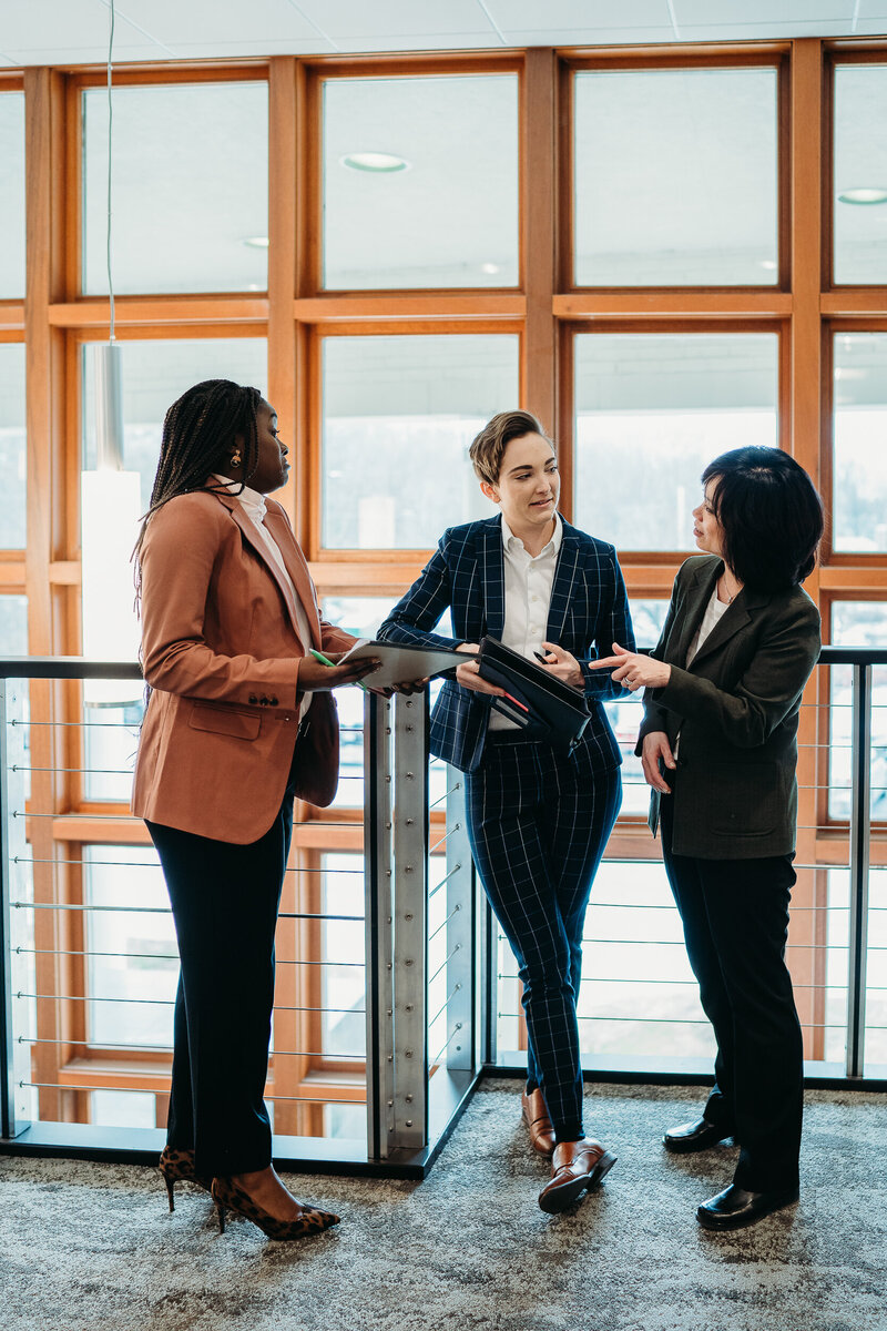 three woman in office building discuss business during commercial brand shoot