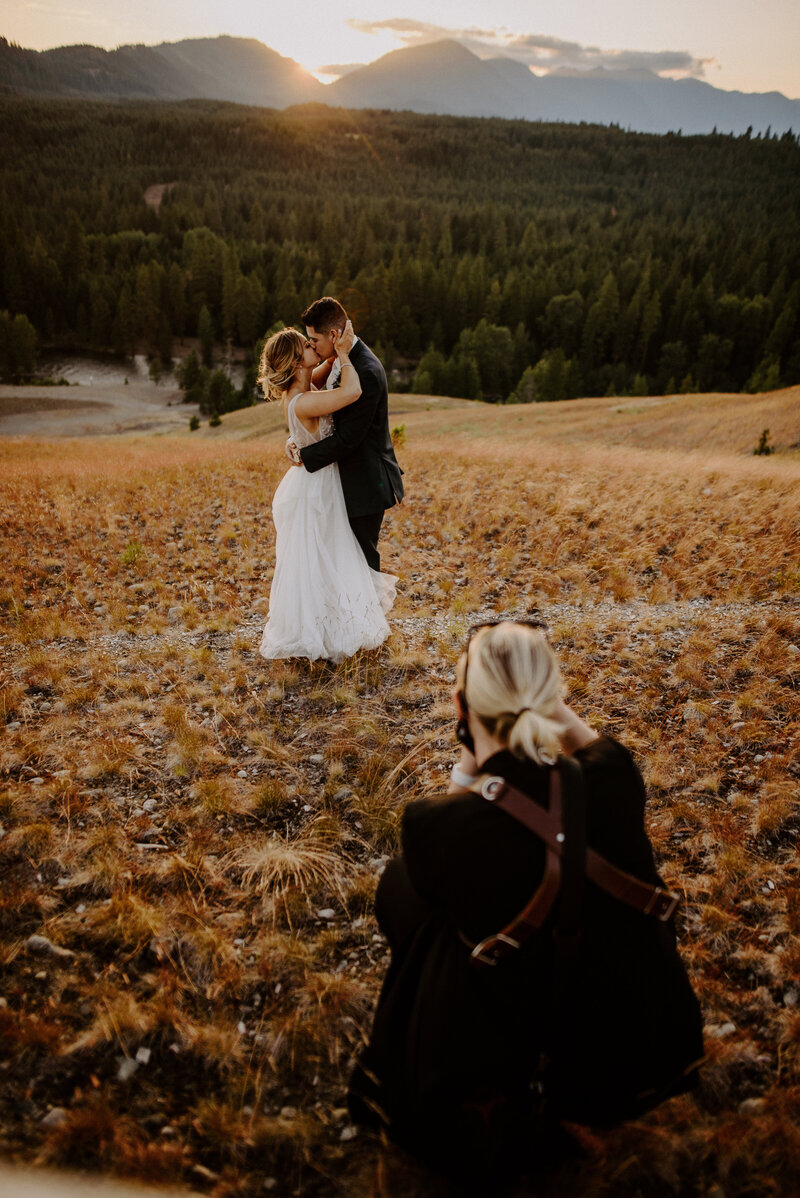 Photographer taking a bride and groom portrait on a mountain top