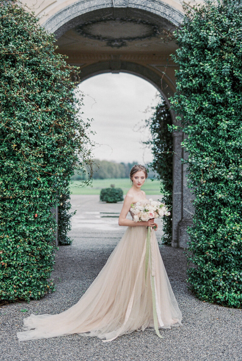 2bride-with-bouquet-stands-near-old-villa-como-italy