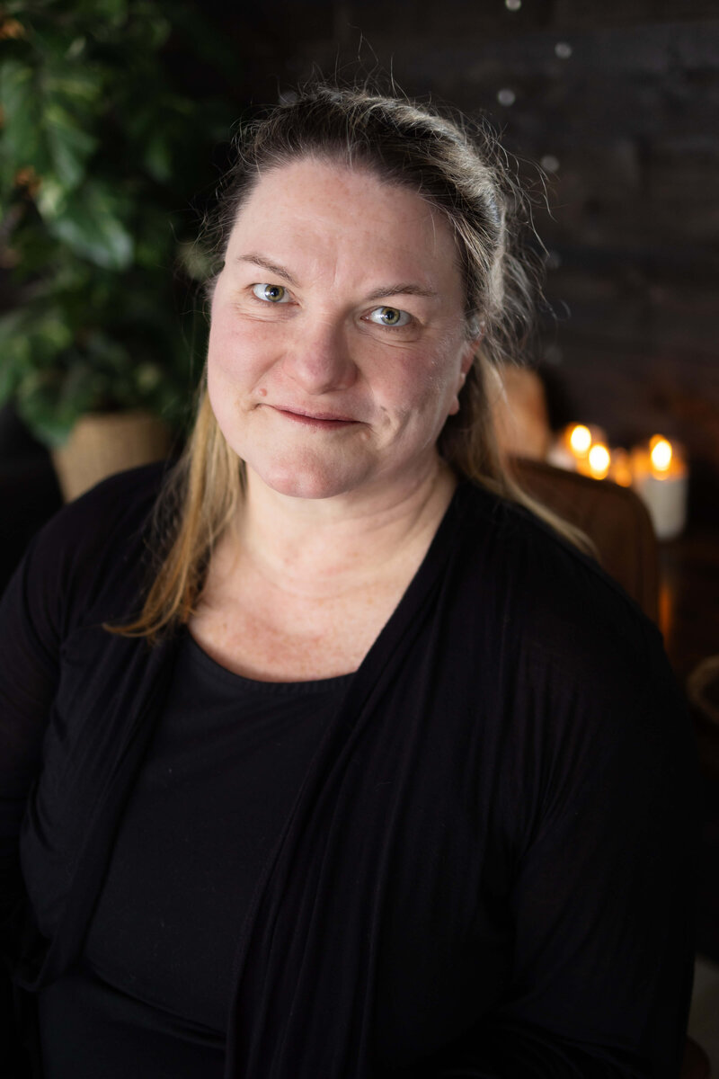 A woman smiling with candles in the background.