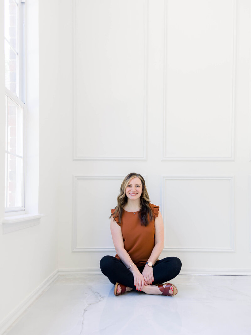 woman in blue jeans smiling with her phone