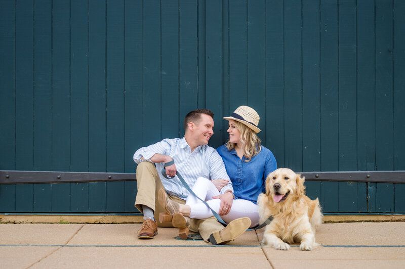 A golden retriever playfully stealing the spotlight during an engagement session with its owners, showcasing the joyful connection and charm their furry friend brings to their special photoshoot.