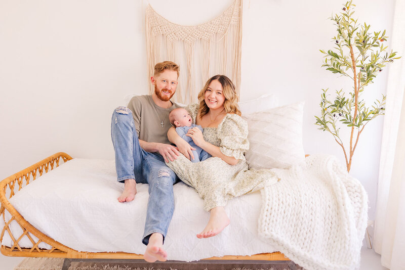 Family of 3 posing during their indoor newborn family lifestyle photoshoot in a studio in Fredrick, Colorado.