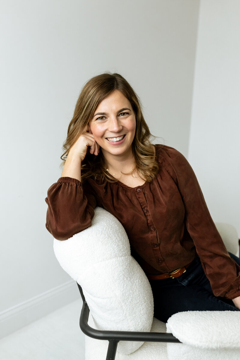Chelsey, Medina, MN therapist at Nova North Therapy, smiling while seated in a chair, wearing a brown blouse.