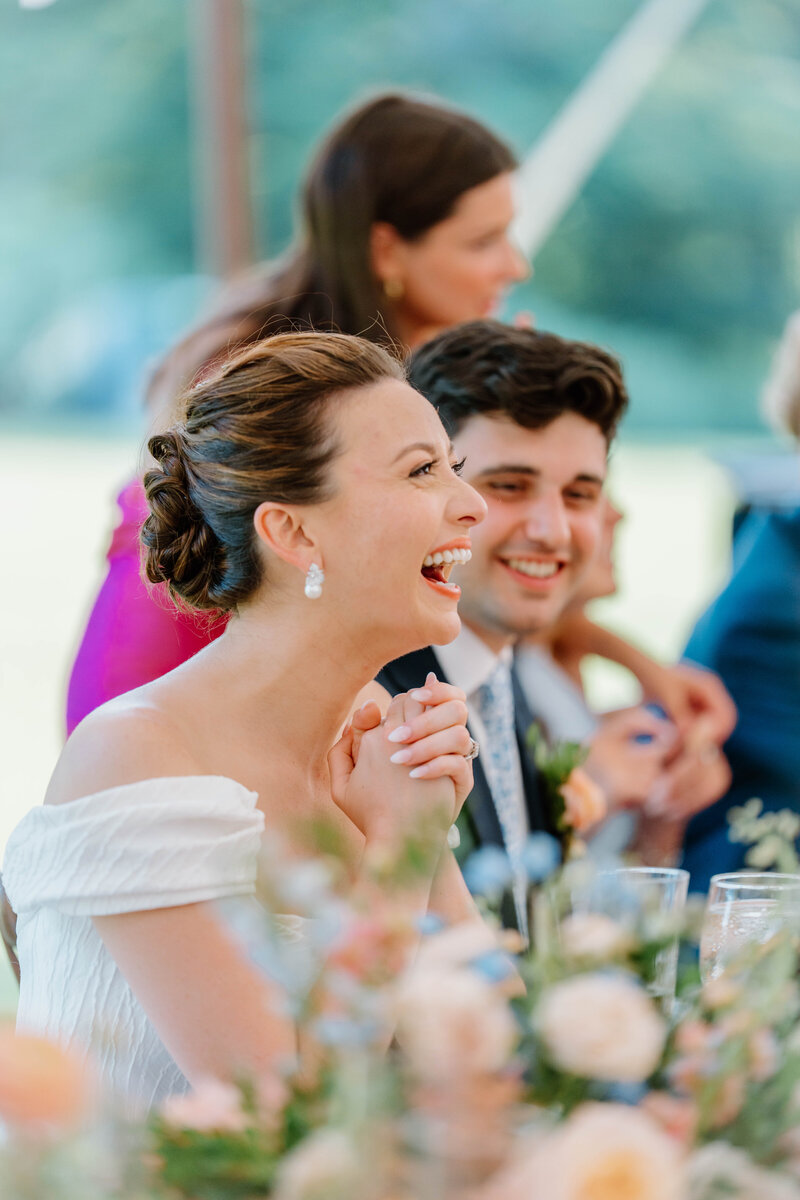 Bride laughing at a speech during wedding reception