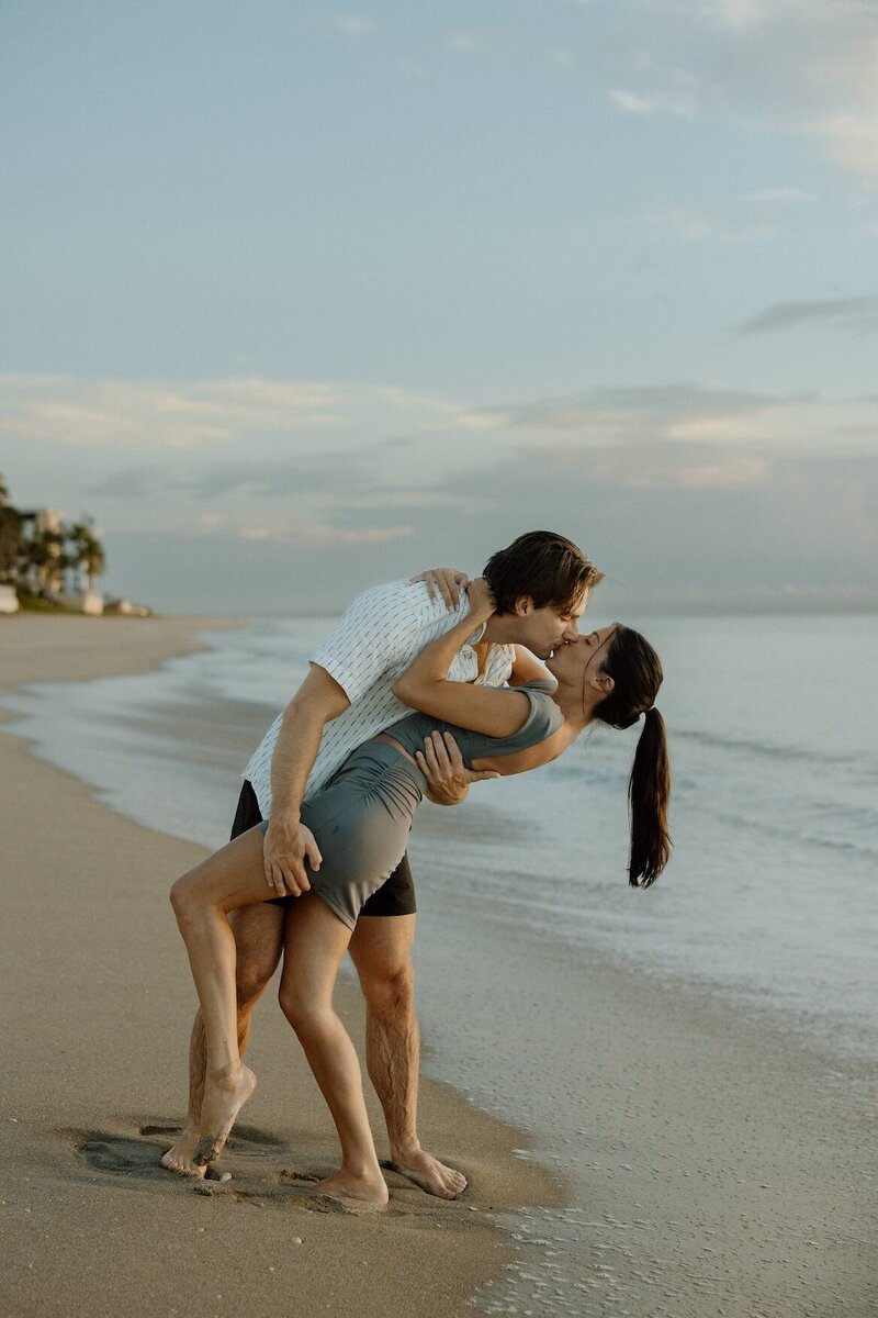 couples shares a kiss on the beach during photoshoot in south florida