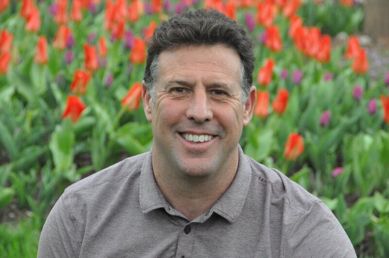 headshot of Embassy Landscape founder, Joe Smith, in front of orange flowers