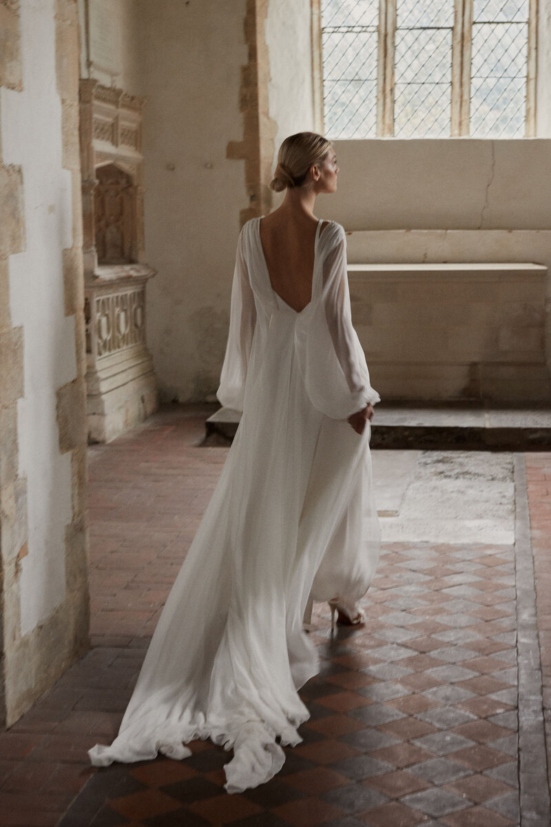 Backless silk flowing wedding dress on bride walking down aisle