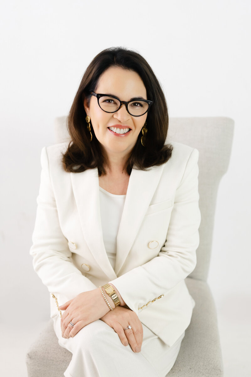 Leadership coach smiling in white suit representing confidence and calm under pressure