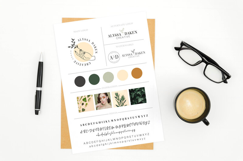 Modern brand design on a piece of paper surrounded by glasses, coffee, and various desk items.