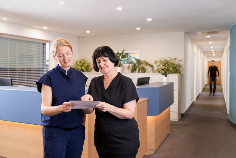 Dentist and receptionist looking over paperwork in waiting room