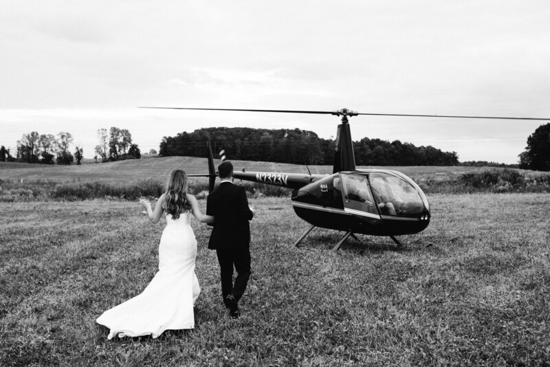 The bride and groom walk together to board a helicopter.