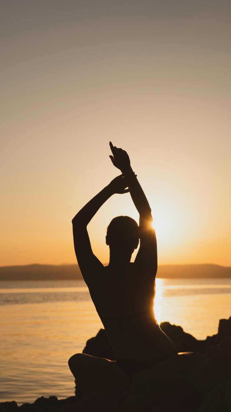 A woman meditating in sunlight feeling grounded and at peace from heart-energy healing