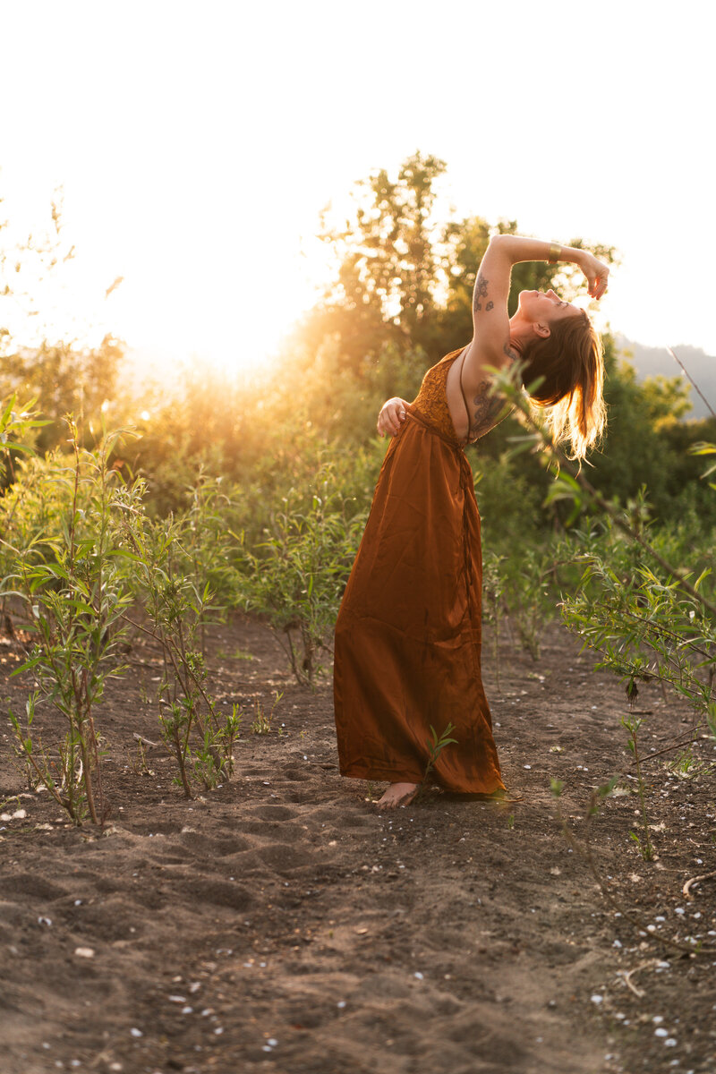 mentor, healer, guide looking to the sky in green field with sunburst behind her