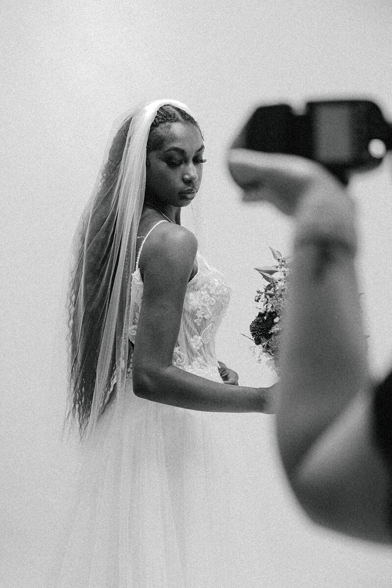 bride posing to a photo while seeing the hand of the photographer
