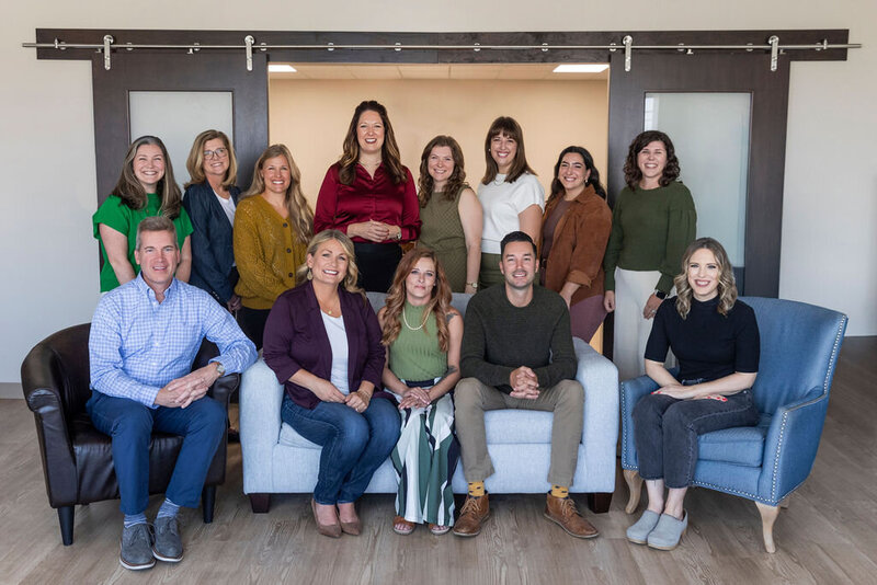 Group of men and women seated and standing around a couch