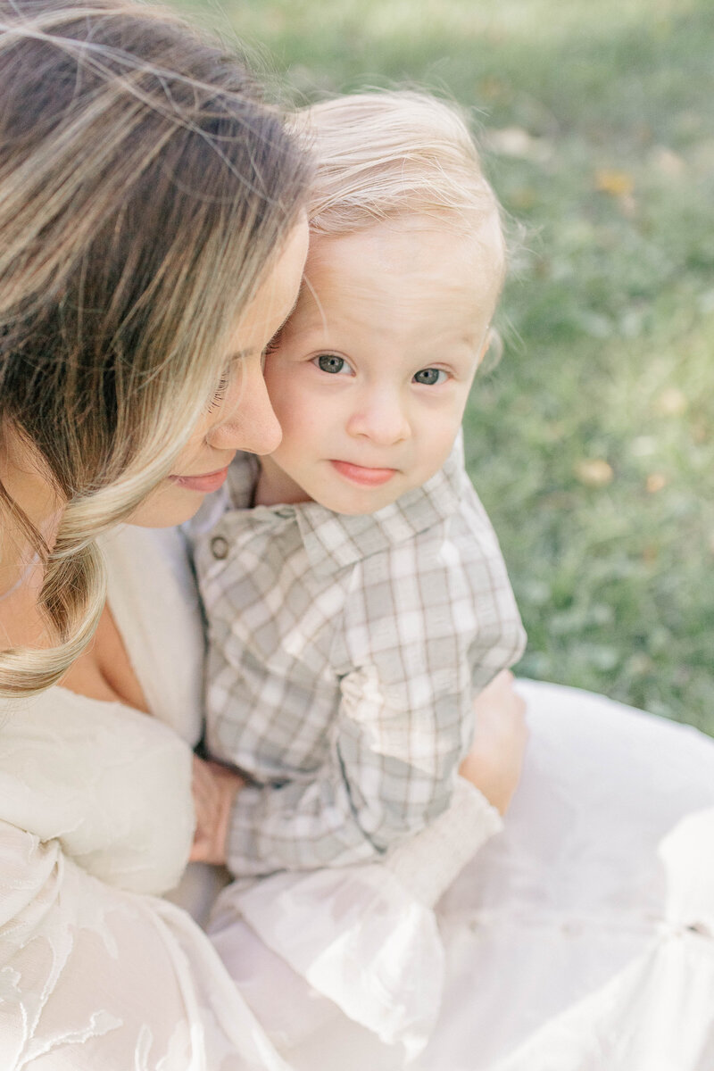 Close-up image of a mother and her toddler son sharing a quiet moment in the grass at a kansas city park